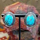 Sterling silver earrings with turquoise set in the bezels, framed by twisted rope and intricate stamping.
