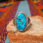 Navajo Turquoise Ring featuring a large elongated oval turquoise stone with natural brown and dark matrix, framed by twisted rope detailing and set in Sterling Silver with a split-shank band.