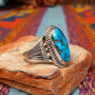 Navajo Turquoise Ring featuring a large elongated oval turquoise stone with natural brown and dark matrix, framed by twisted rope detailing and set in Sterling Silver with a split-shank band; side view.