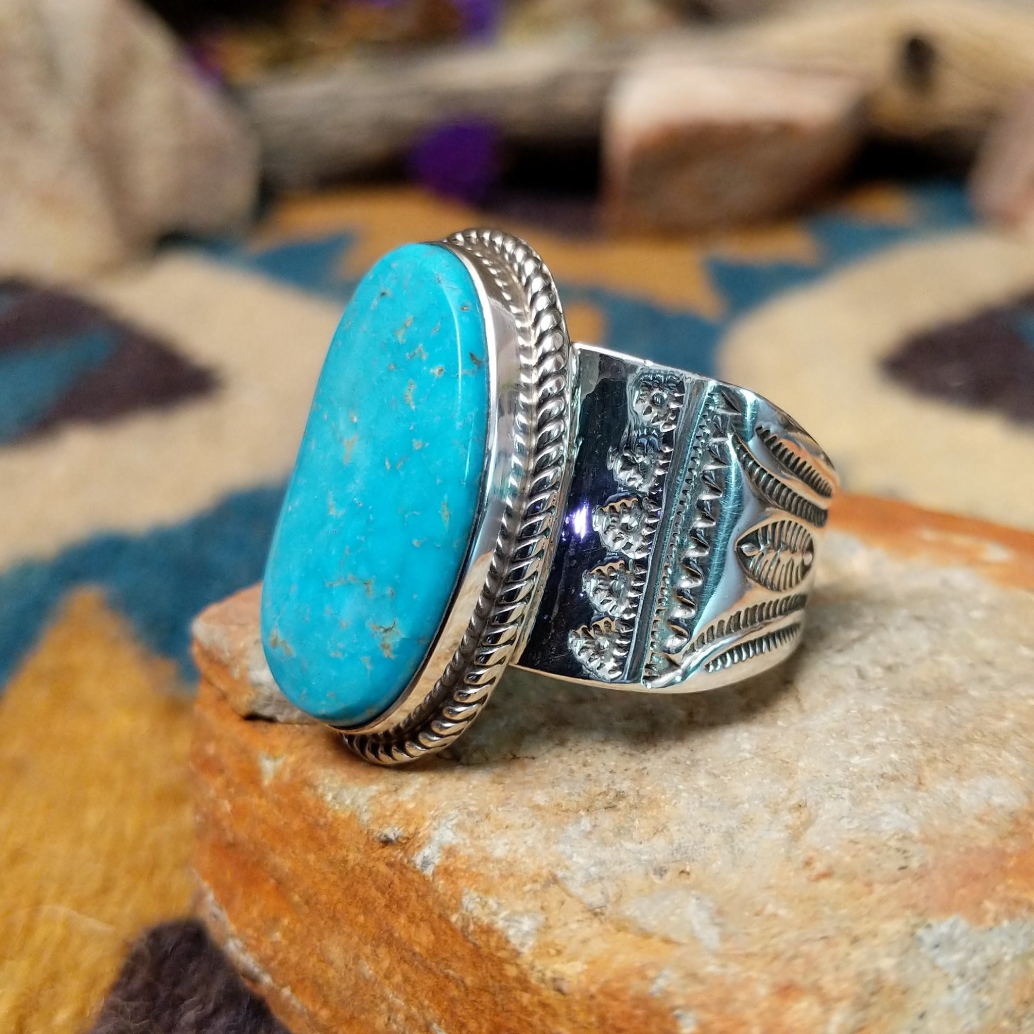Handcrafted Navajo sterling silver ring by L.P. featuring a large oval natural turquoise cabochon with subtle golden matrix, set in a twisted rope bezel on a wide hand-stamped split-shank band; side view.