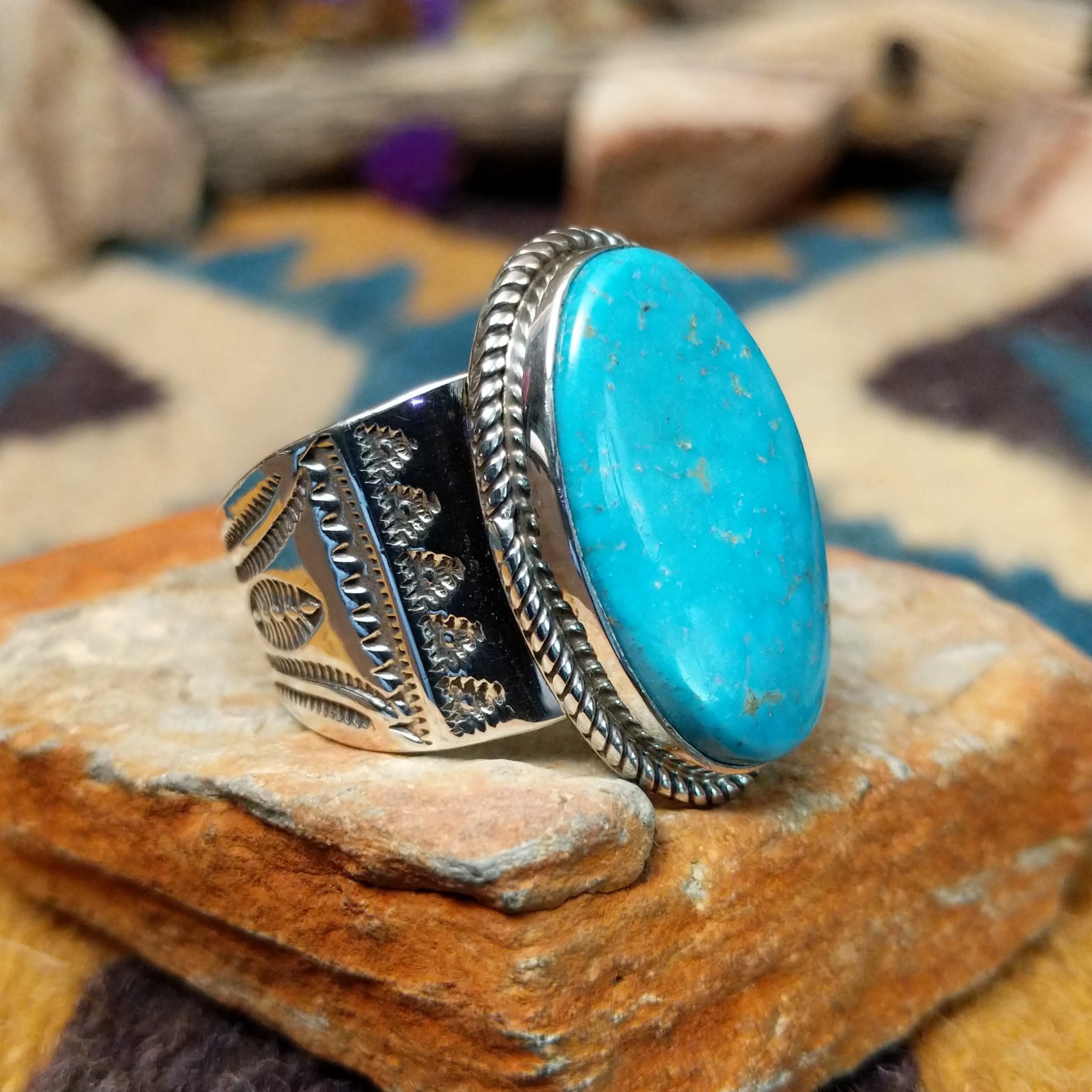 Handcrafted Navajo sterling silver ring by L.P. featuring a large oval natural turquoise cabochon with subtle golden matrix, set in a twisted rope bezel on a wide hand-stamped split-shank band; side view.