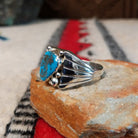 Navajo turquoise ring by S. with silver drops and tapered band.