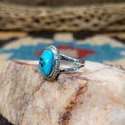 Navajo turquoise ring by S.S., featuring a vibrant blue turquoise stone with natural black matrix, surrounded by a twisted rope border and set in a handcrafted sterling silver split shank band.  Side view.