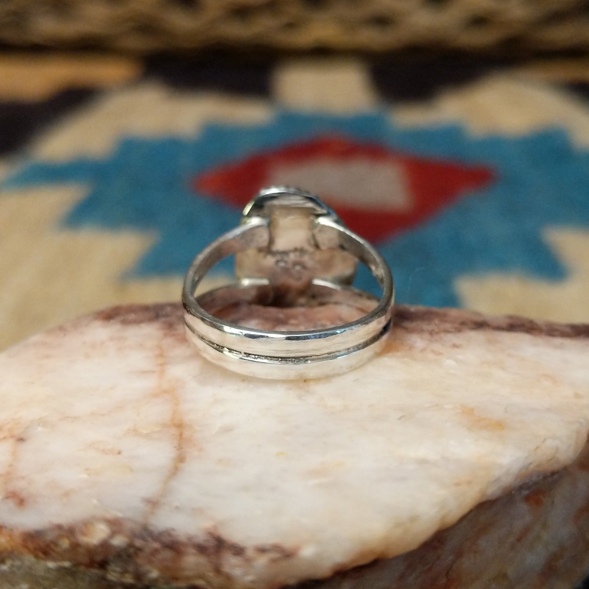 Navajo turquoise ring by S.S., featuring a vibrant blue turquoise stone with natural black matrix, surrounded by a twisted rope border and set in a handcrafted sterling silver split shank band.  Underside view.