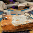 Handcrafted sterling silver Navajo cuff by E. featuring a vibrant row of turquoise channel inlay with a polished silver frame and scalloped edge detailing; underside view.