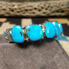 Navajo turquoise septet cuff, featuring seven blue turquoise stones with natural matrix set in a handcrafted sterling silver cuff; side view.