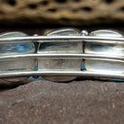 Navajo turquoise septet cuff, featuring seven blue turquoise stones with natural matrix set in a handcrafted sterling silver cuff; artisan and Sterling Silver stamp.