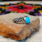 This graceful Navajo Twisting Turquoise Ring features a rounded sky-blue turquoise stone with subtle natural matrix, set in a smooth silver bezel on a twisted silver band; side view.