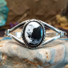 Sterling silver cuff bracelet with a white buffalo stone set in a round bezel, framed by incised lining and a layered band.