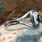 Sterling silver cuff bracelet with a white buffalo stone set in a round bezel, framed by incised lining and a layered band.