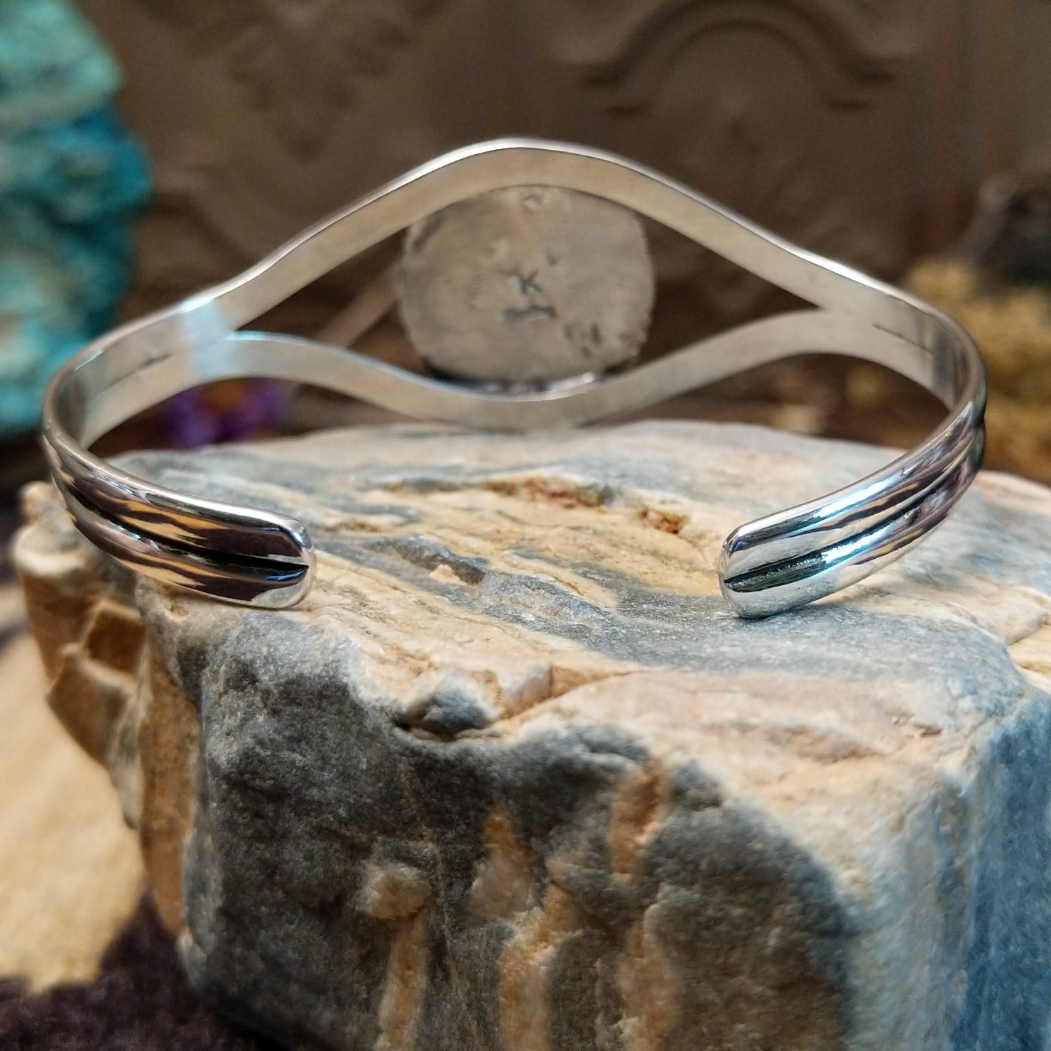 Sterling silver cuff bracelet with a white buffalo stone set in a round bezel, framed by incised lining and a layered band.