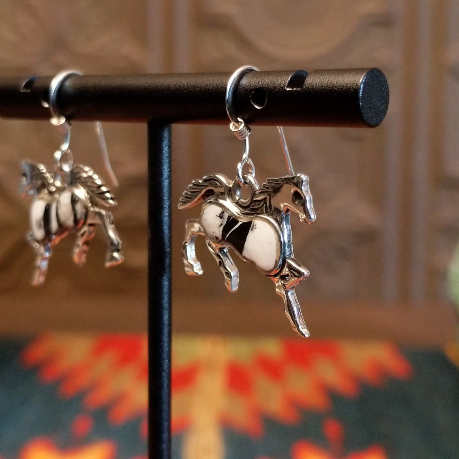 Sterling silver horse earrings with white buffalo stones set in the centers.