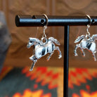 Sterling silver horse earrings with white buffalo stones set in the centers.