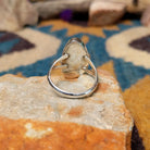 Handcrafted Navajo sterling silver ring featuring an elongated oval White Buffalo inlay with black onyx, turquoise, and sterling silver geometric accents in a polished bezel setting; underside view.