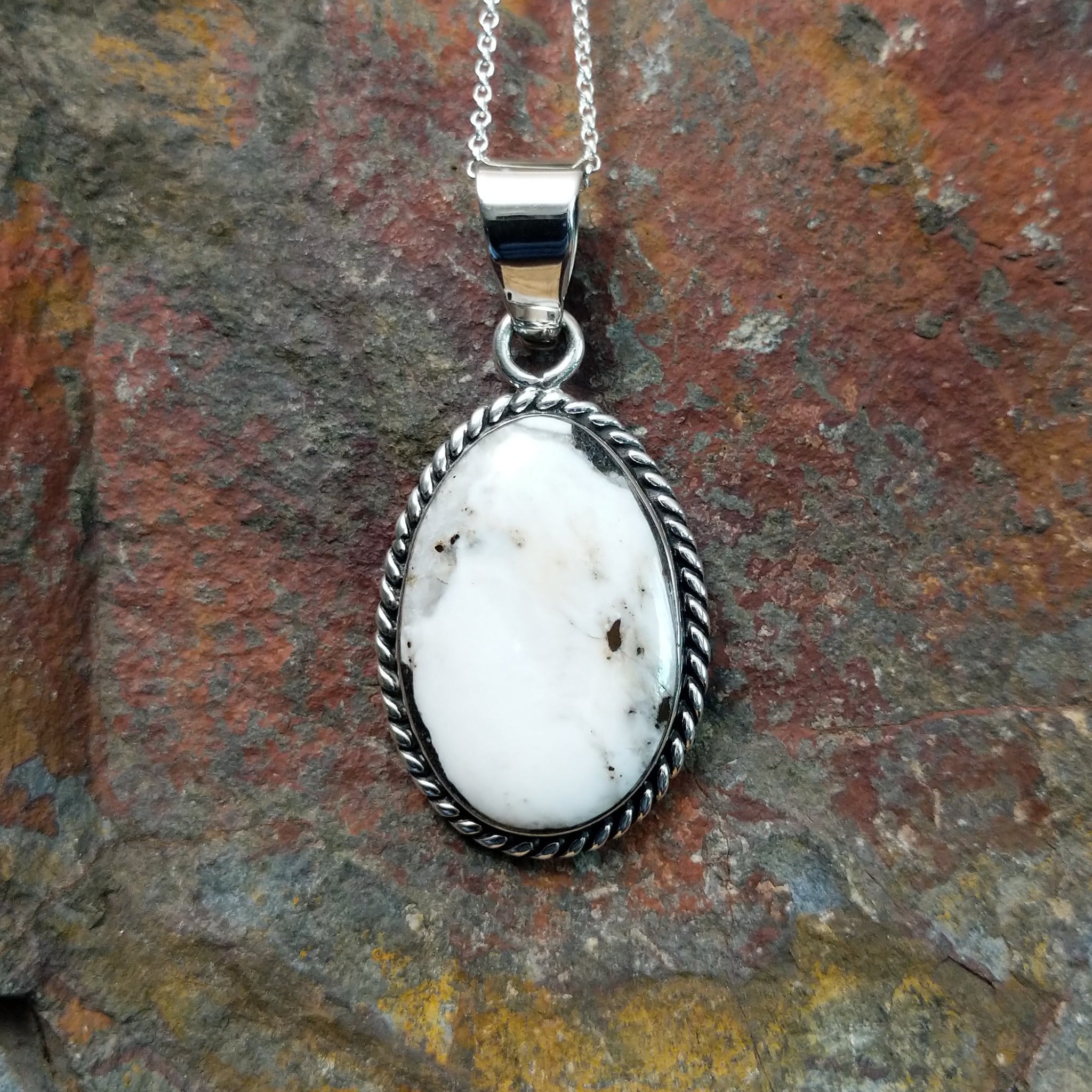 Handcrafted sterling silver Navajo White Buffalo portrait pendant by K., featuring a natural White Buffalo gemstone in a twisted rope bezel setting.