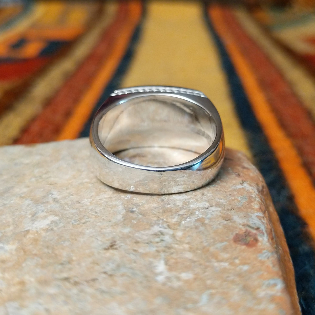 This elegant Navajo White Buffalo with Turquoise Inlay Ring features a rectangular silver setting with black-and-white White Buffalo stone and vibrant turquoise inlay arranged in a flowing geometric pattern; underside view.