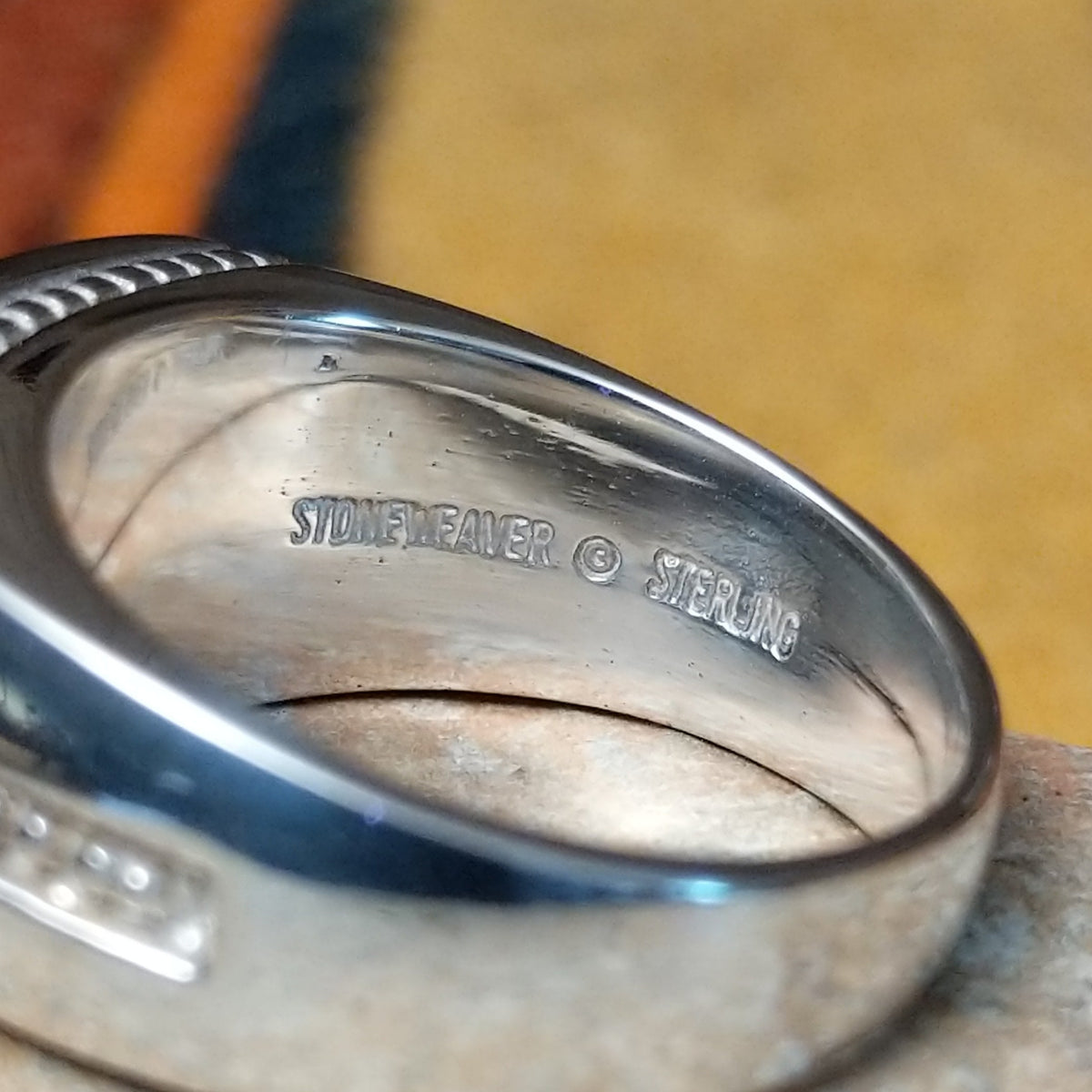This elegant Navajo White Buffalo with Turquoise Inlay Ring features a rectangular silver setting with black-and-white White Buffalo stone and vibrant turquoise inlay arranged in a flowing geometric pattern; artisan and Sterling Silver stamp.