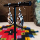 Navajo Wild Horse Teardrop Earrings by B.A. featuring polished white and reddish-brown matrix stones in detailed silver settings with French ear wires; side view.