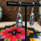 Navajo Wild Horse Teardrop Earrings by B.A. featuring polished white and reddish-brown matrix stones in detailed silver settings with French ear wires; side view.