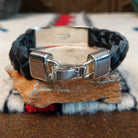 Navajo bracelet with braided black leather and a rectangular polished silver centerpiece featuring repeating stepped geometric patterns and central triangular designs; clasp view.