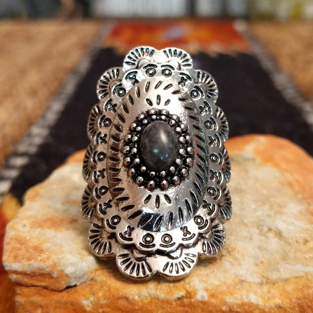A nickel-free metal ring with a dark stone center, framed by dotted and patterned edges.