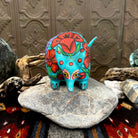 Armadillo figurine in bright teal with orange flowers, featuring small black eyes and yellow accents.