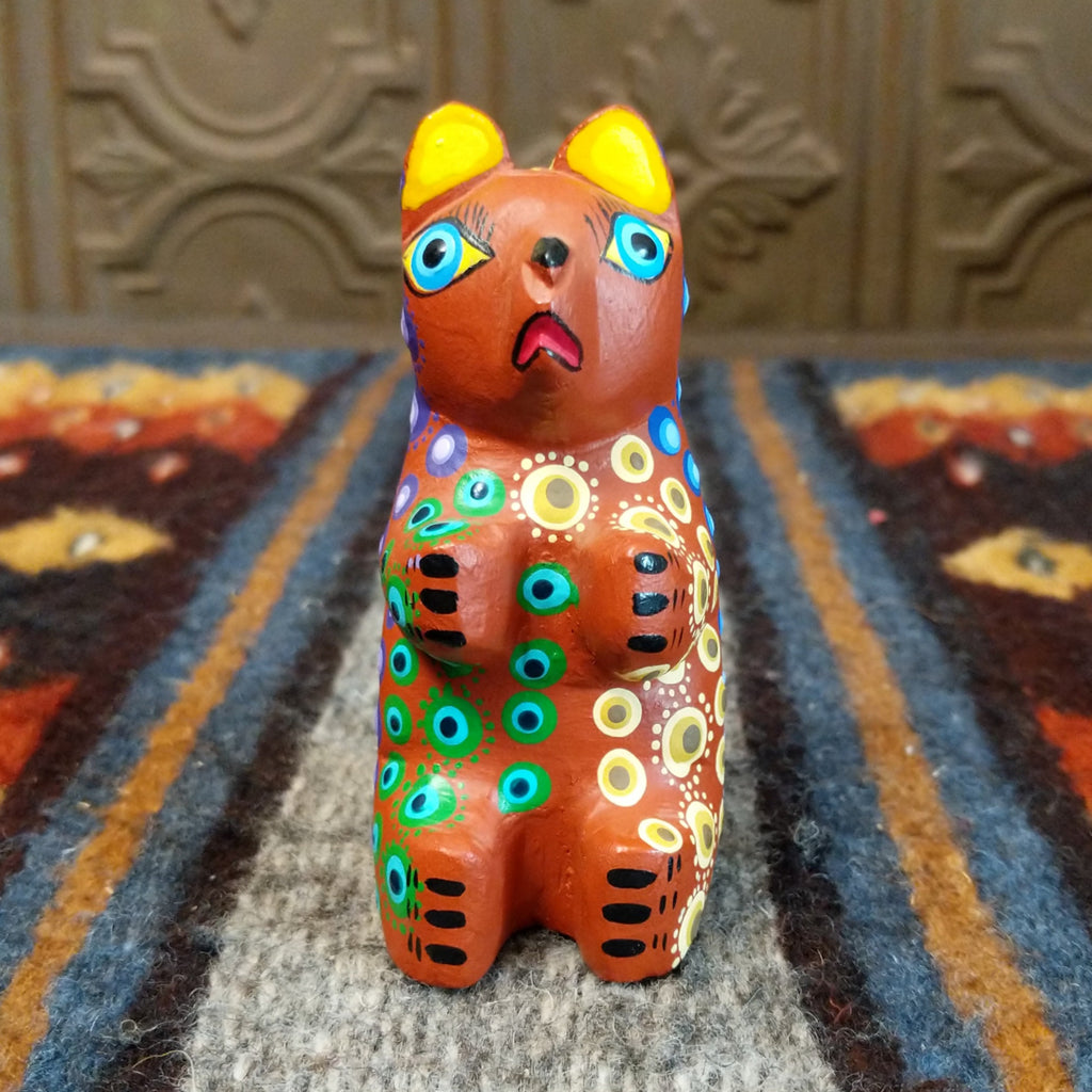 Oaxacan bear wood carving painted in rich brown, adorned with vibrant multicolor patterns.