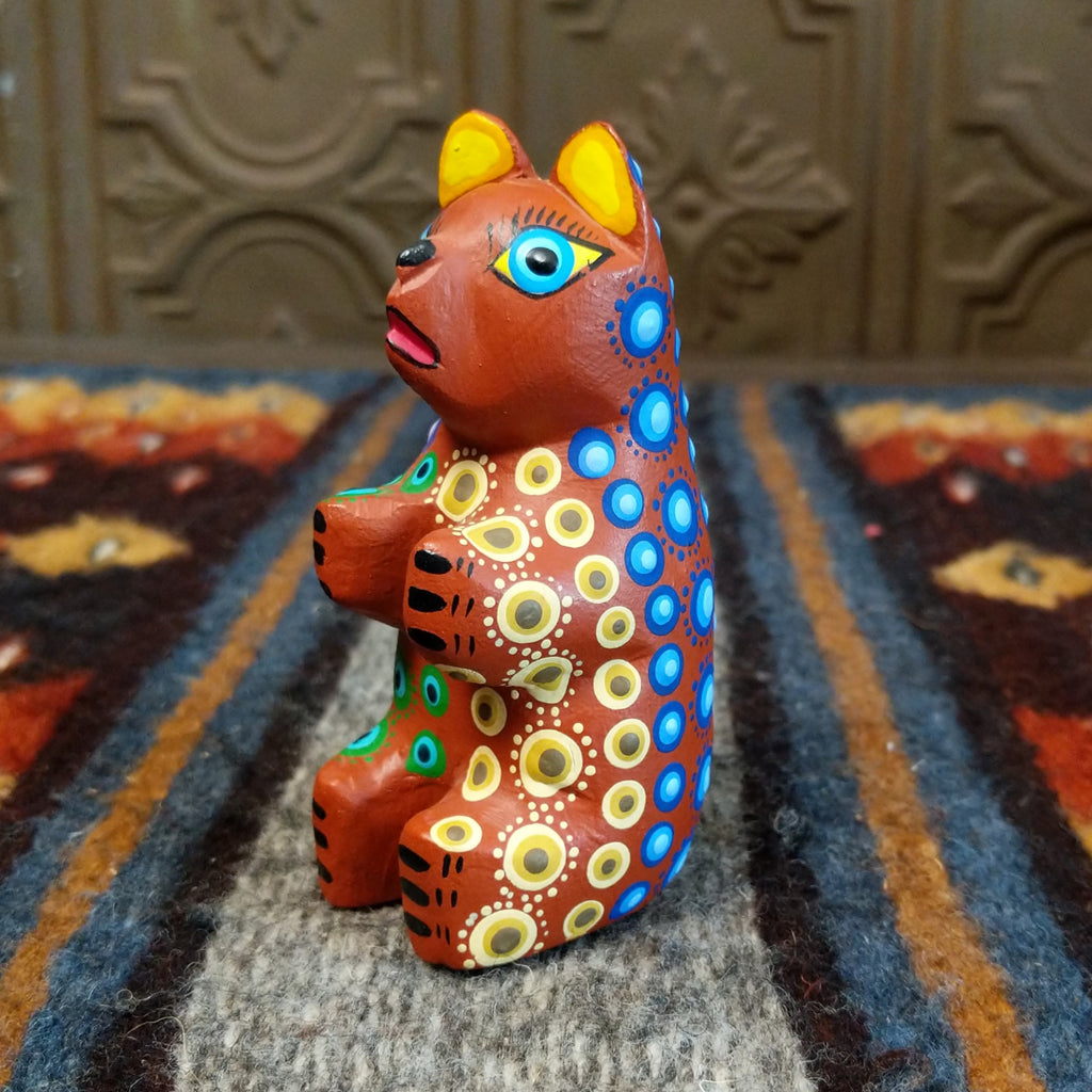 Oaxacan bear wood carving painted in rich brown, adorned with vibrant multicolor patterns.