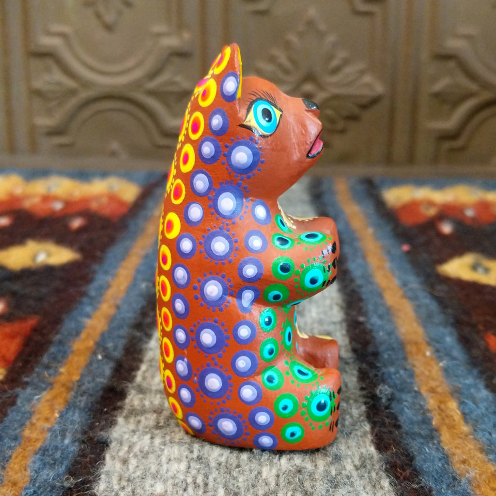 Oaxacan bear wood carving painted in rich brown, adorned with vibrant multicolor patterns.