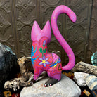 Pink cat figurine adorned with purple and yellow floral patterns across its chest.