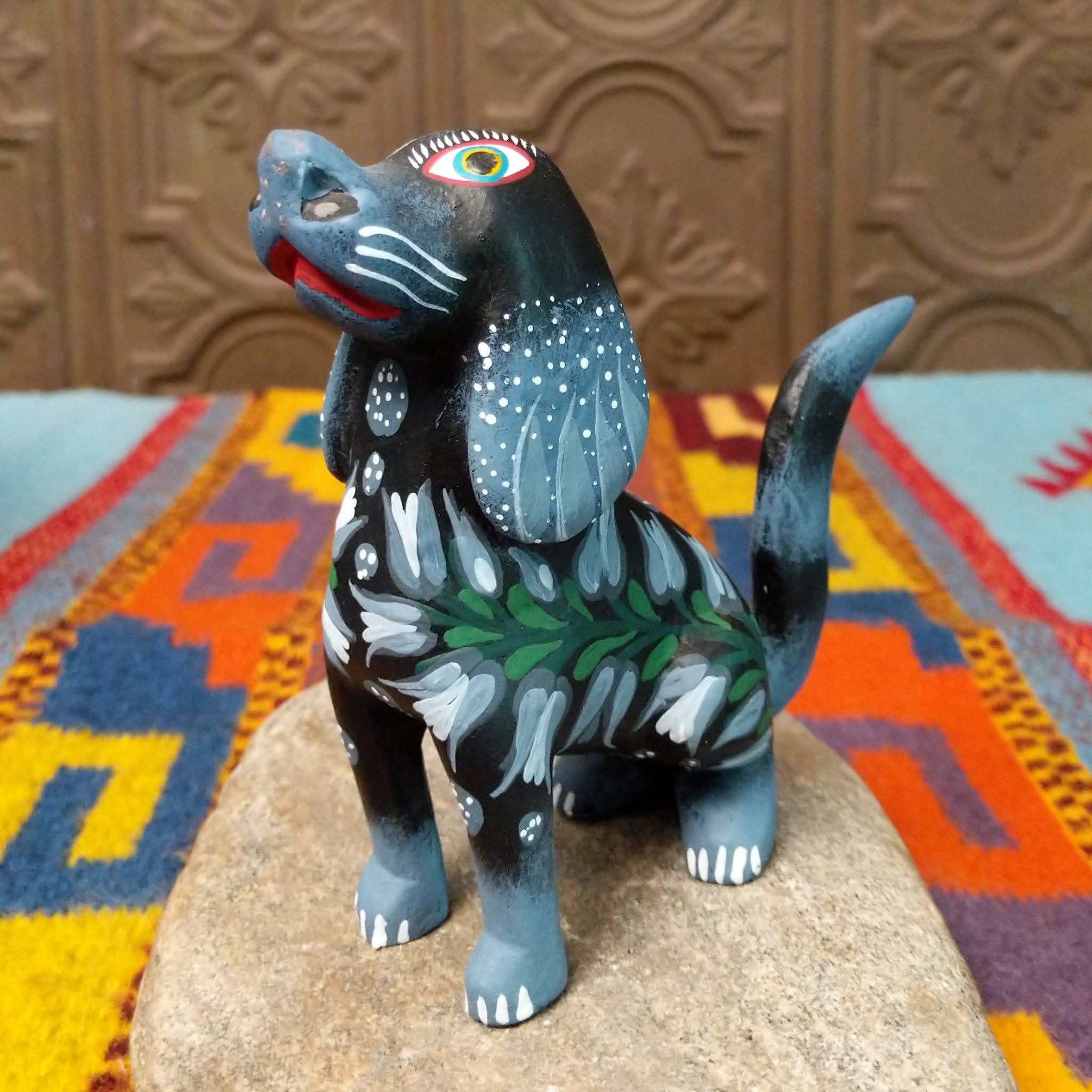 Oaxacan dog wood carving by Jose Olivera Perez with an open mouth, raised curved tail, and hand-painted floral and leafy designs.
