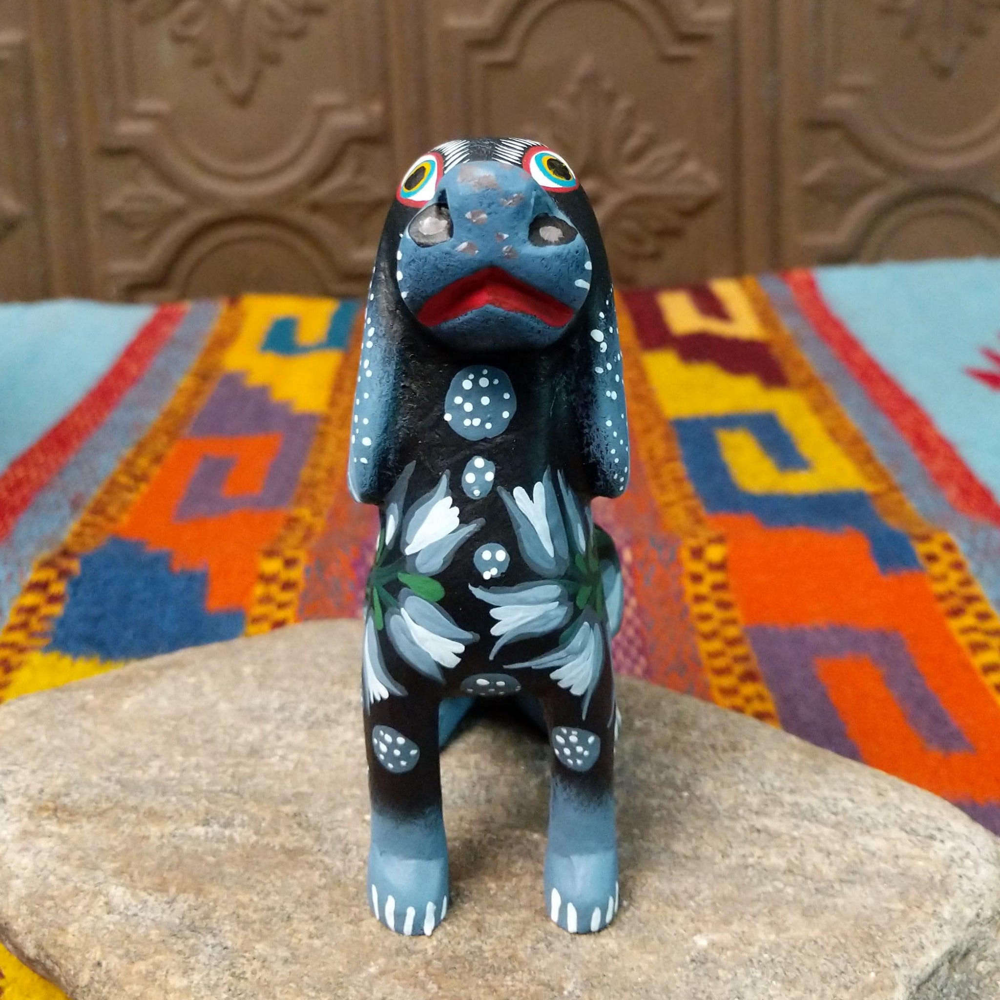 Oaxacan dog wood carving by Jose Olivera Perez with an open mouth, raised curved tail, and hand-painted floral and leafy designs.