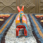 Oaxacan donkey wood carving painted in bold red and vibrant designs.