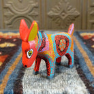 Oaxacan donkey wood carving painted in bold red and vibrant designs.