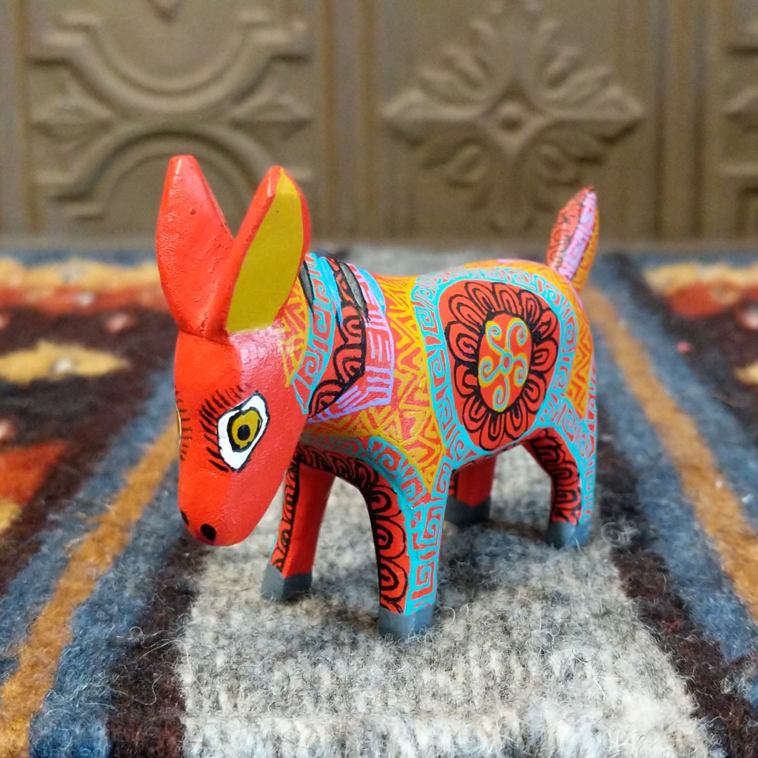 Oaxacan donkey wood carving painted in bold red and vibrant designs.