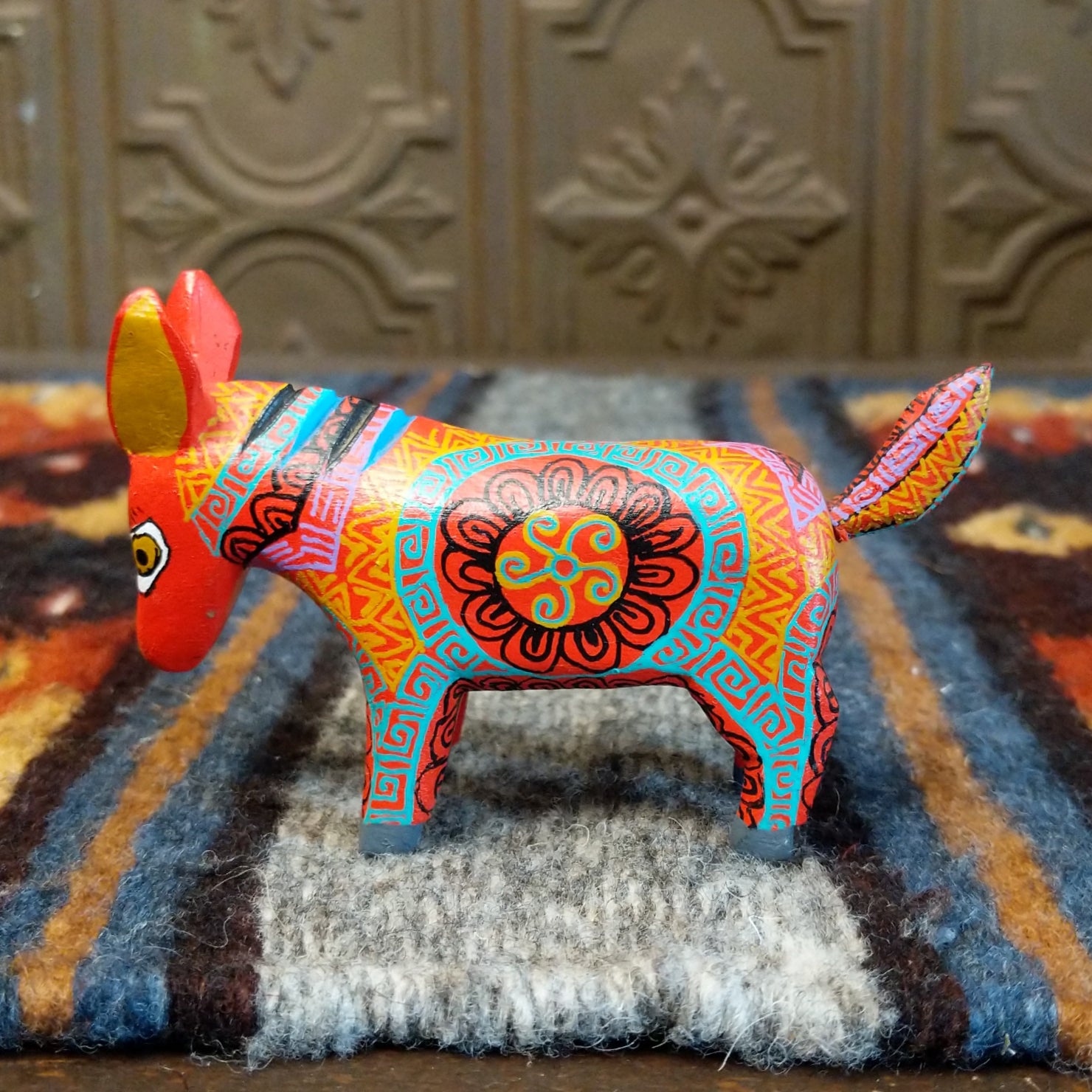Oaxacan donkey wood carving painted in bold red and vibrant designs.