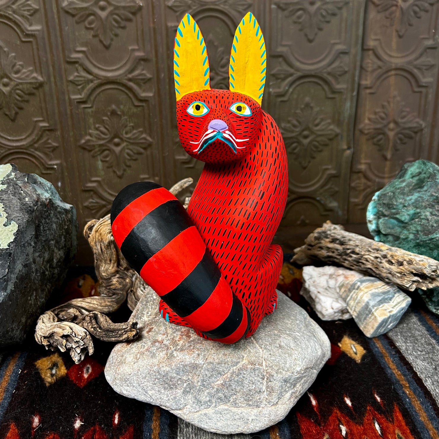 Red fox figurine with yellow ears accented in blue, featuring wide yellow eyes and intricate black stippling across its face.