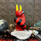 Red fox figurine with yellow ears accented in blue, featuring wide yellow eyes and intricate black stippling across its face.