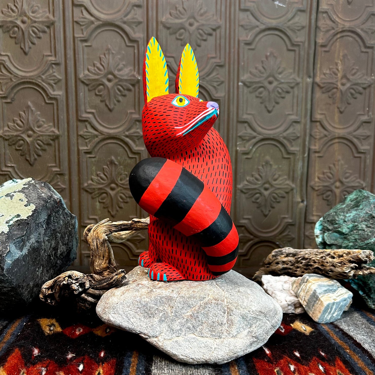 Red fox figurine with yellow ears accented in blue, featuring wide yellow eyes and intricate black stippling across its face.