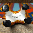 This Oaxacan giraffe wood carving by Faviola Fabian features a golden-yellow body with reddish-brown spots, a long neck, blue eyes, black-and-white horns, and black hooves; artisan name and location of production.