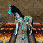 Oaxacan horse carving painted in vibrant colors, with black string hair forming a flowing mane.