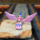 Oaxacan hummingbird carving painted in soft pink, with vibrant colorful accents on its body.