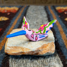 Oaxacan hummingbird carving painted in soft pink, with a striking blue beak and red floral accents on its wings.