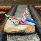 Oaxacan hummingbird carving painted in soft pink, with a striking blue beak and red floral accents on its wings.