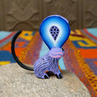 Oaxacan jerboa wood carving with oversized blue patterned ears, a lavender body, orange front legs, and long curved black tail.