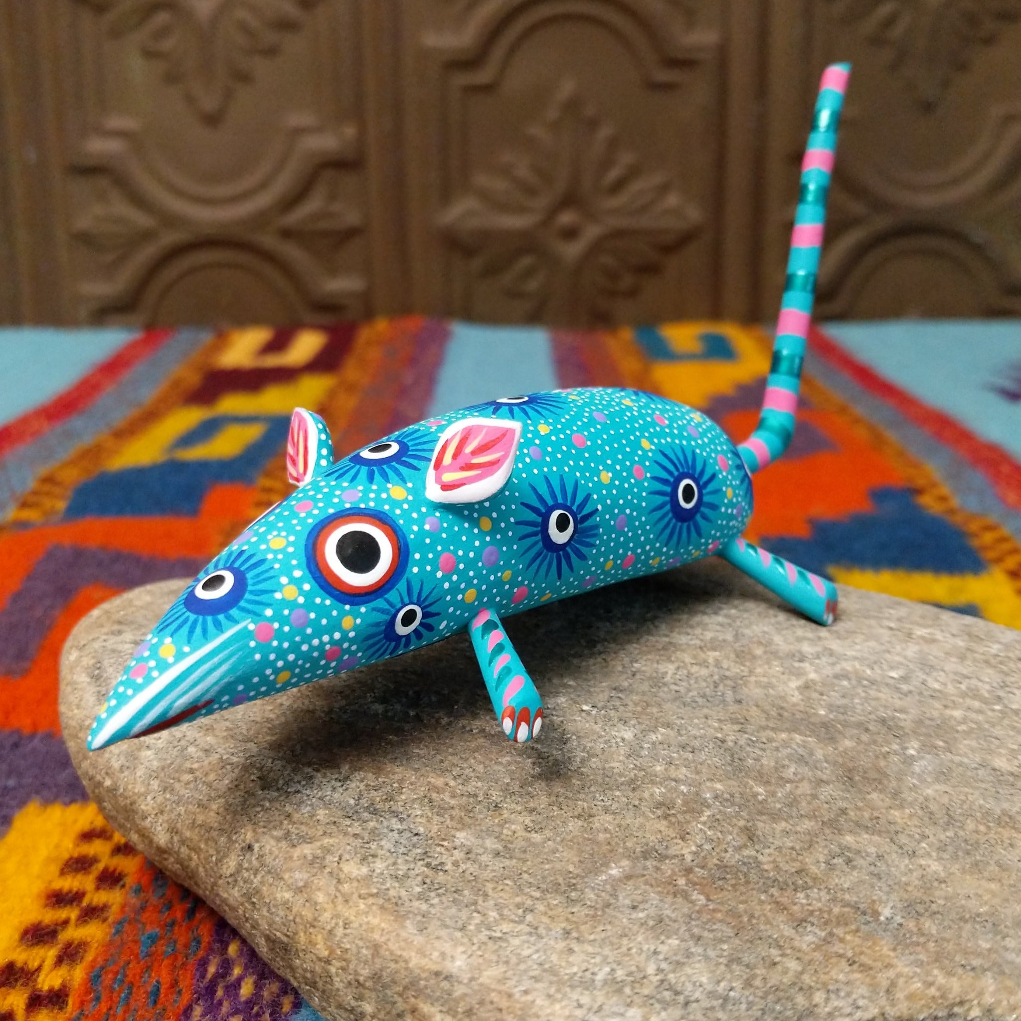 This turquoise Oaxacan mouse wood carving by Fabian Ramirez features colorful hand-painted patterns, pink-accented ears and legs, and a long striped tail.