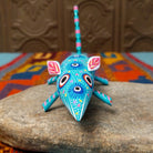 This turquoise Oaxacan mouse wood carving by Fabian Ramirez features colorful hand-painted patterns, pink-accented ears and legs, and a long striped tail.