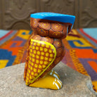 Oaxacan owl wood carving with a rounded body, large circular eyes, painted feather patterns, and a broad blue brow.