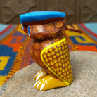 Oaxacan owl wood carving with a rounded body, large circular eyes, painted feather patterns, and a broad blue brow.
