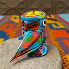 Oaxacan owl wood carving with oversized round eyes and a colorful patchwork of birds, leaves, dots, and abstract painted designs.